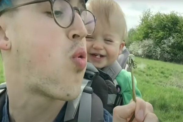 Dad blows a dandelion and kid laughs